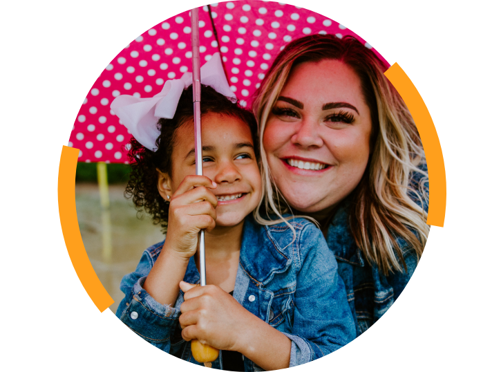 Woman and girl smiling under umbrella