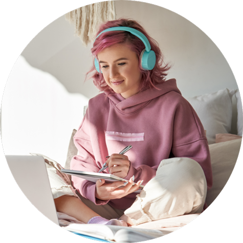 Girl sitting on bed with headphones studying